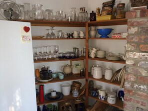 A kitchen with shelves stocked with glassware, plates, and jars. - Gorgeous 3-bedroom house with AC in West Tisbury (West Tisbury)