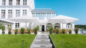 A white building with a central entrance, two large white umbrellas, and a paved pathway leading to the entrance. - 6 Person Holiday Park Home in Glindow (Werder (Havel))