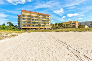 Un hôtel situé en bord de mer, doté de nombreux balcons et donnant sur une plage de sable.