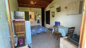A compact kitchen with a stove, a sink, and a dining area with a table and chairs. - Gîte Studio Omu di Cagna (Monacia-d'Aullène)