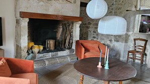 Ein Wohnzimmer mit Kamin, Fernseher, rundem Tisch mit Kerzen und orangefarbener Möbel.