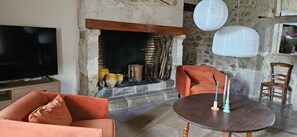 Ein Wohnzimmer mit Kamin, Fernseher, rundem Tisch mit Kerzen und orangefarbener Möbel.