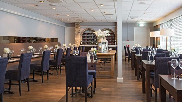 Un ristorante con diversi tavoli e sedie, una credenza per vini e una parete in pietra.