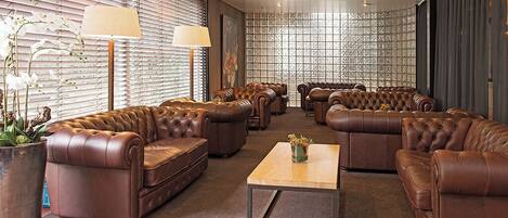 A spacious lounge area with leather sofas, a central coffee table, and a patterned wall.