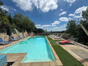 A rectangular swimming pool with a clear blue water surface, surrounded by a stone deck and artificial grass.