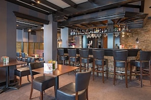 A bar area with multiple seating options, a bar counter with bottles, and a stone wall backdrop. - Modern Room with Garden Access and Free Parking in Vlijmen, Near Nature Trails (Vlijmen)