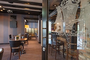 Un interior de restaurante con mesas, sillas y una puerta de vidrio decorativa.