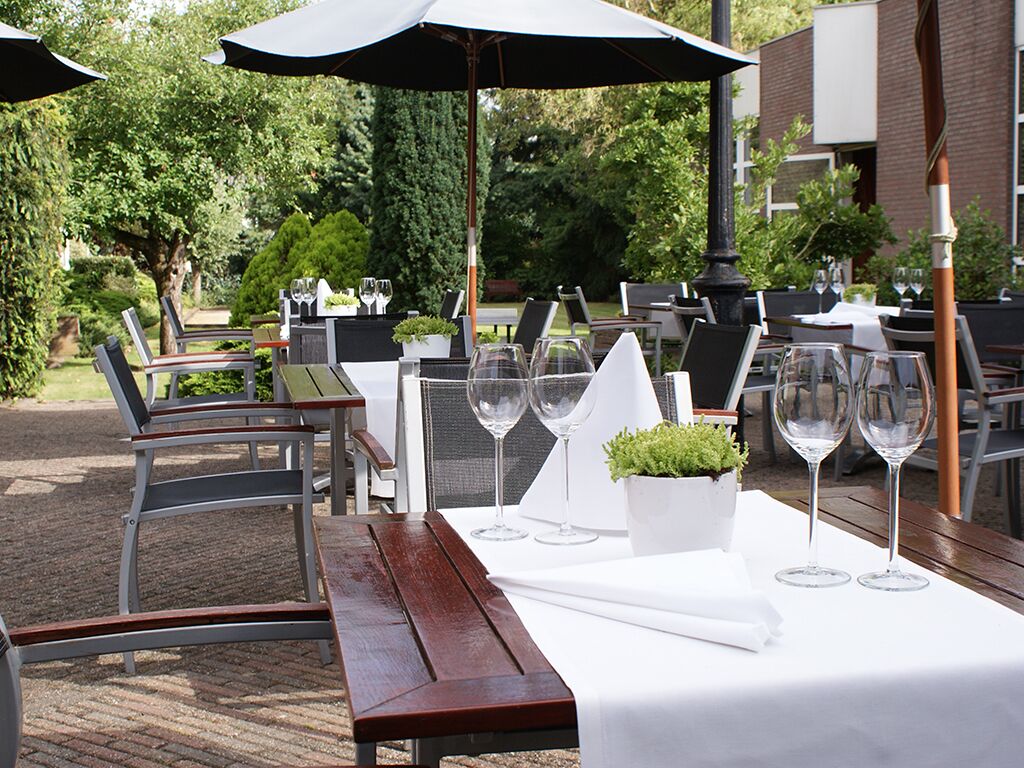 Un espace extérieur aménagé pour les repas, avec des tables, des chaises et des parasols.