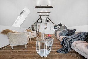 A loft-style living room with a high ceiling, a skylight, a round metal table, and a sofa with a fur throw. - Liegeplatz 3 - Balcony, Fireplace, Rain Shower, Water View, Private Parking (Glücksburg)