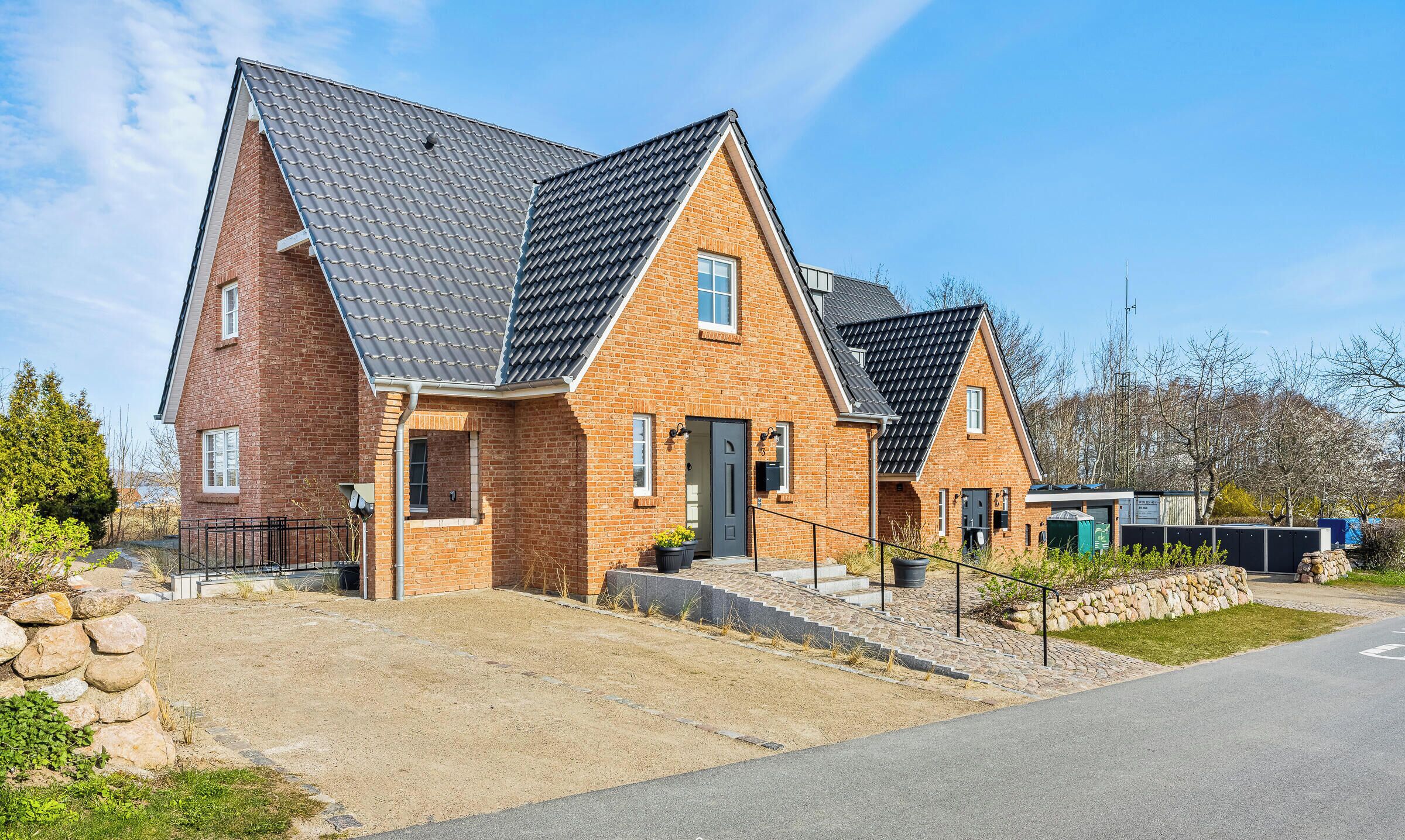 A two-story house with a brick facade, a sloped roof, and a front entrance with steps leading up to it.
