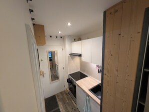 Une cuisine de taille réduite, dotée d’un plan de travail en bois, d’une cuisinière et de placards.