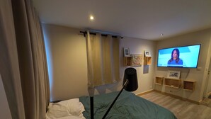 Ein Schlafzimmer mit einem Bett, einem Fernseher, einer Lampe und Wandregalen.