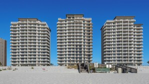 Three high-rise buildings with multiple balconies, a sandy beach in the foreground, and a clear blue sky. - 🌞🩴Gulf-Front 3BR | Great Amenities + Steps to Beach | Summerwind West 1403 (Navarre Beach)
