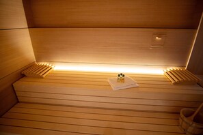 Eine Sauna mit Holzbänken, einem Handtuch und Ölflaschen.