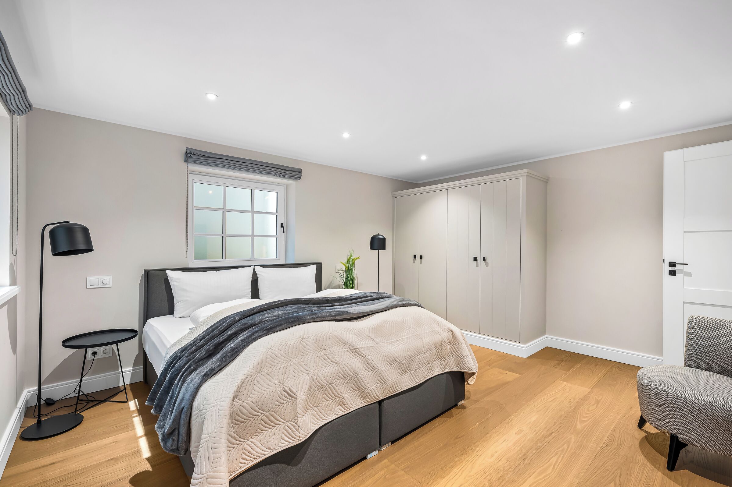 Ein Schlafzimmer mit Bett, Nachttischen, einem Kleiderschrank und einem Sessel.