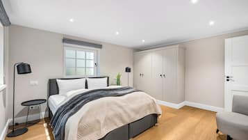 Ein Schlafzimmer mit Bett, Nachttischen, einem Kleiderschrank und einem Sessel.