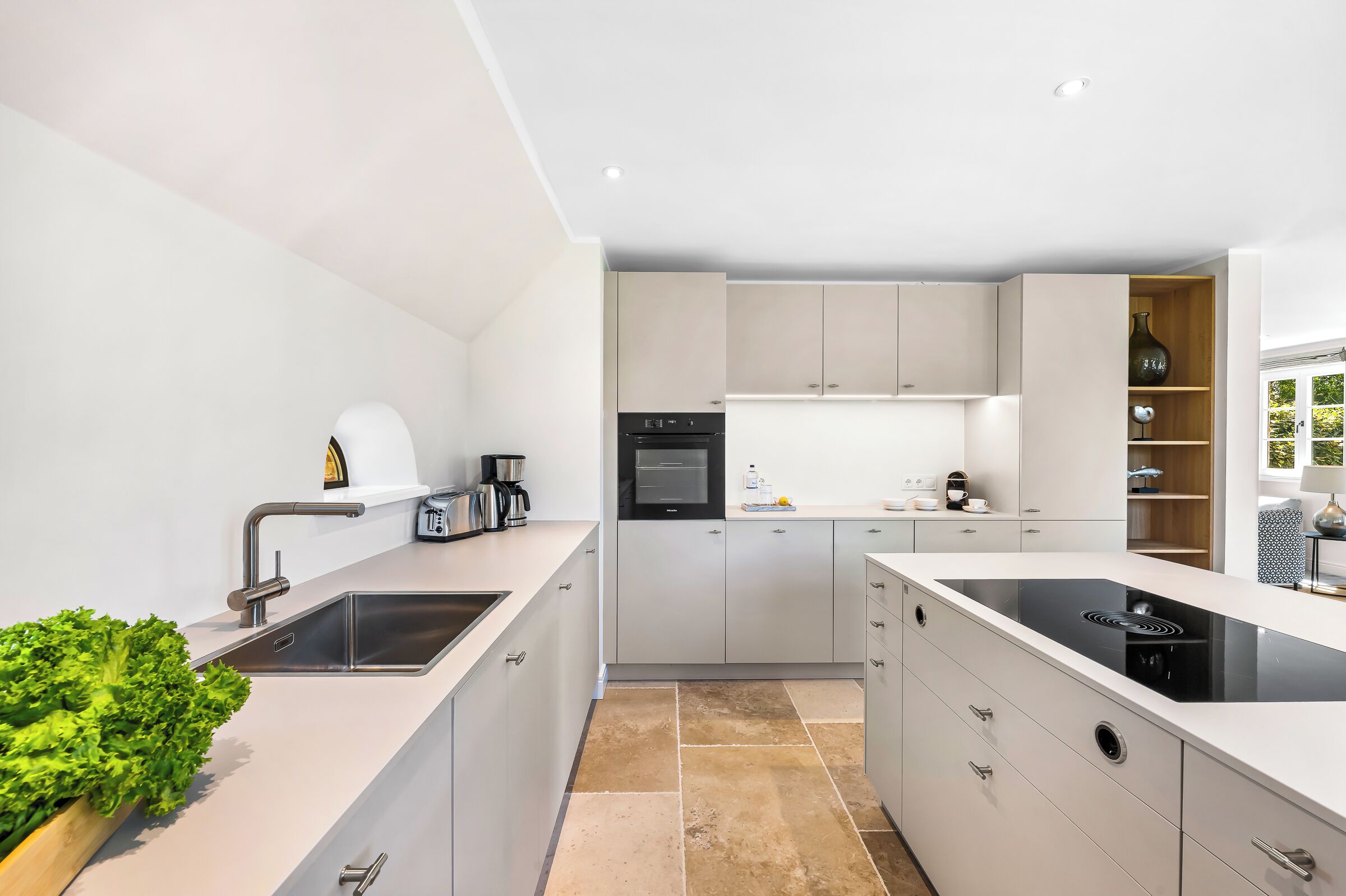 A modern kitchen with a built-in oven, a coffee machine, and a sink.