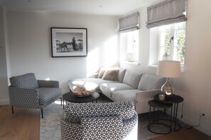 Ein Wohnzimmer mit Sofa, Sessel, Couchtisch und Lampe.