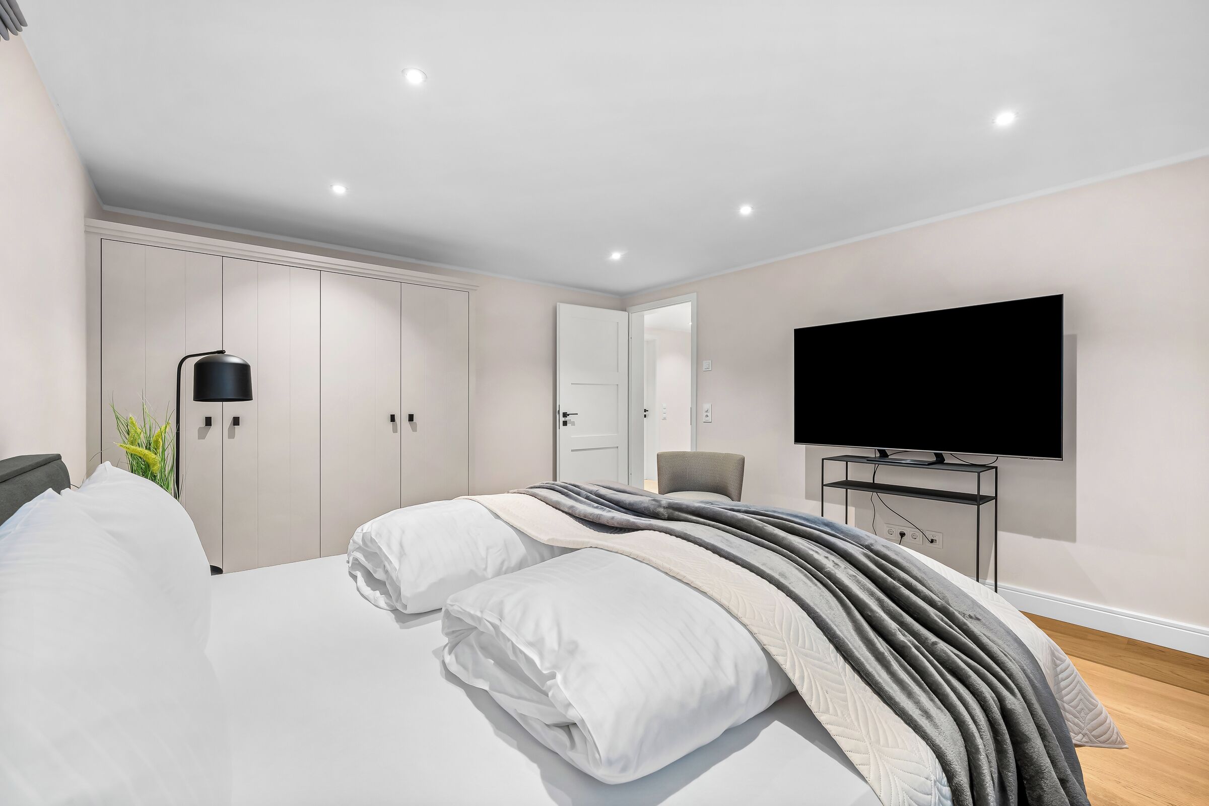 Ein Schlafzimmer mit Bett, Fernseher, Kleiderschrank und Schreibtisch.