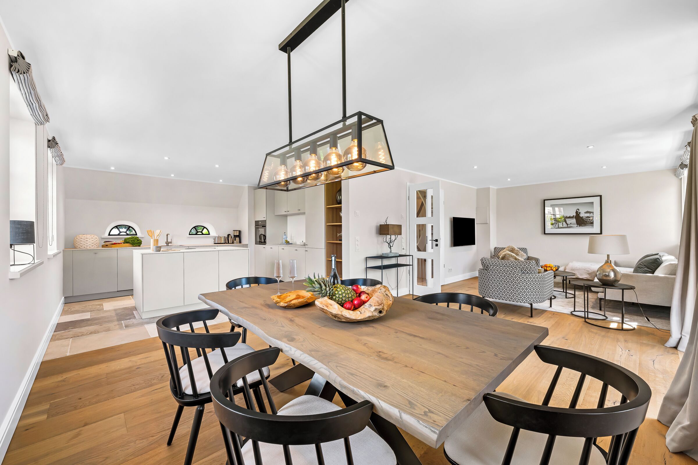 Una cocina moderna con armarios blancos, una mesa de comedor de madera y sillas negras.