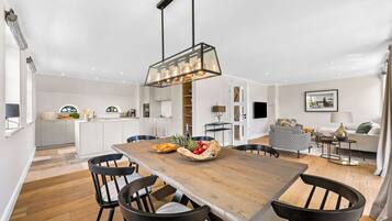 Una cocina moderna con armarios blancos, una mesa de comedor de madera y sillas negras.