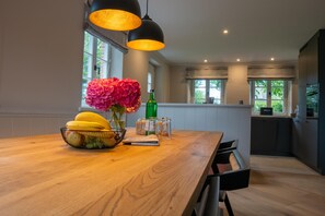 Eine moderne Küche mit Holztisch, Blumen in einer Vase und Pendelleuchten.