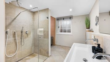 Ein modernes Badezimmer mit einer gläsernen Duschkabine, einer großzügigen Badewanne und einem Fenster für natürliches Licht.