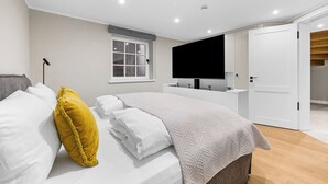 Quarto moderno com uma cama, televisão e banheiro.