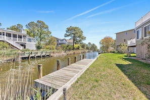 A riverside property with a wooden dock, a grassy lawn, and modern houses. - Lake View Drive House (Bethany Beach)