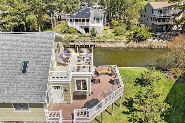 A multi-level house with a deck, outdoor furniture, and a pond. - Lake View Drive House (Bethany Beach)