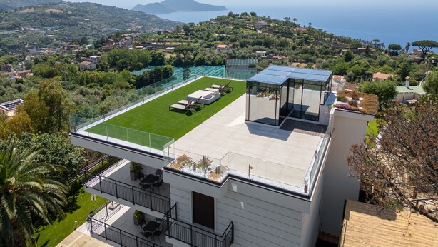 A modern building with a rooftop pool, a glass conservatory, and a view of the sea and hills. - Villa Meridia (Massa Lubrense)