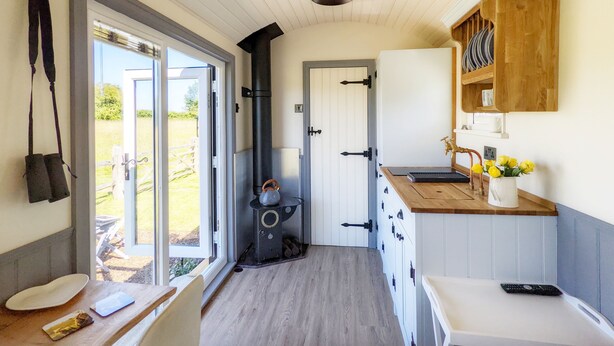 A narrow kitchen with a wooden counter, a stove, and a white door leading outside. - A lodge/cabin that sleeps 2 guests  in 1 bedroom - 3 nights for the price of 2 nights in July! (Ringwood)