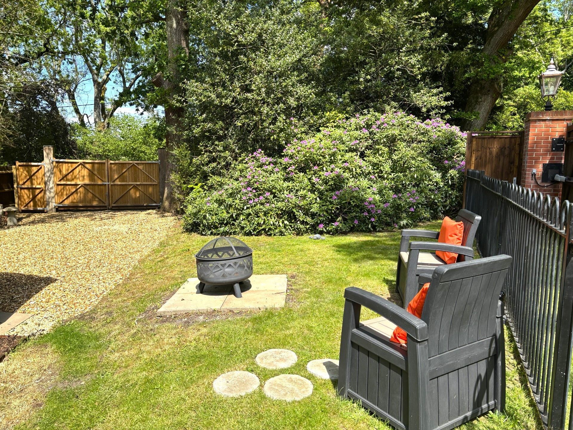 A backyard with a fire pit, outdoor seating, a wooden fence, and a brick structure.