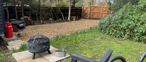 A backyard with a fire pit, outdoor furniture, a wooden fence, and a garden area.
