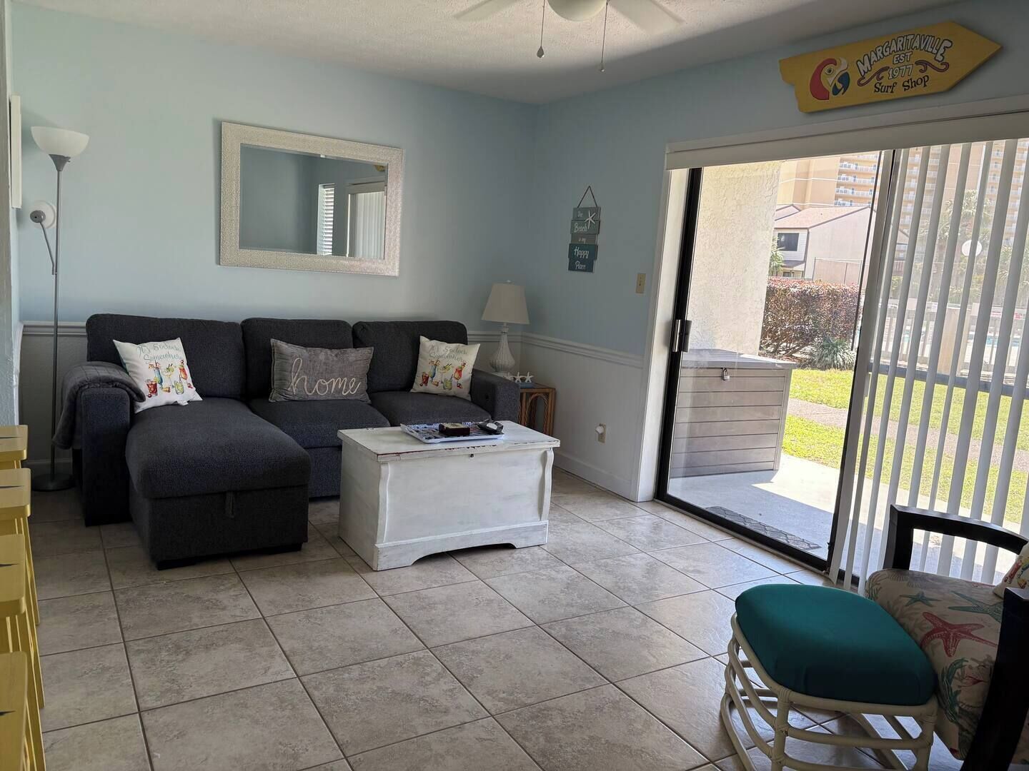 A living room with a sofa, a coffee table, a chair, and a sliding glass door leading to an outdoor area.