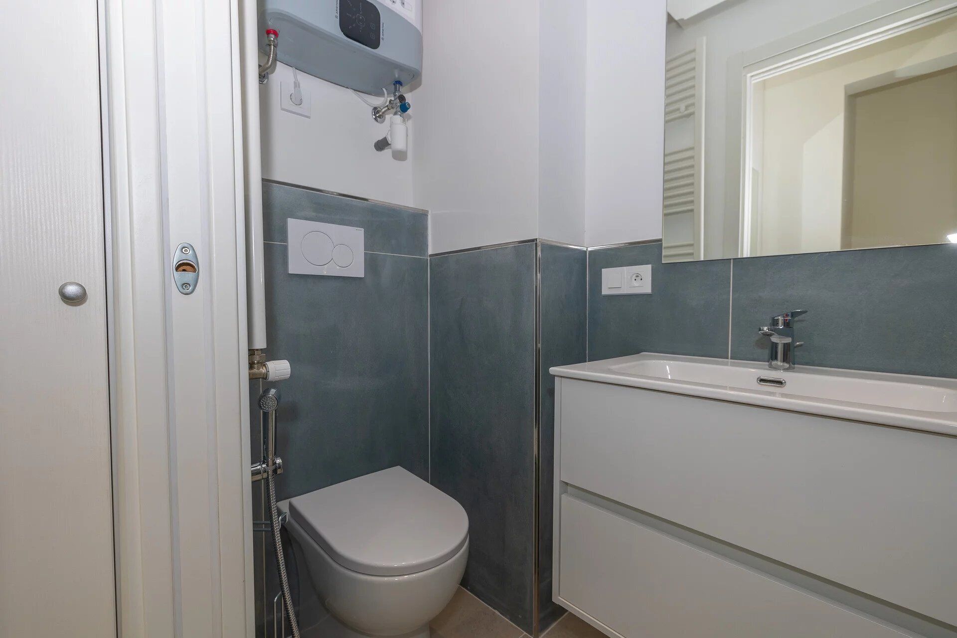 A bathroom with a toilet, a shower, a sink, and a mirror.