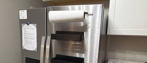 Un réfrigérateur en acier inoxydable doté de quatre étagères, un four à micro-ondes et un plan de travail en bois.