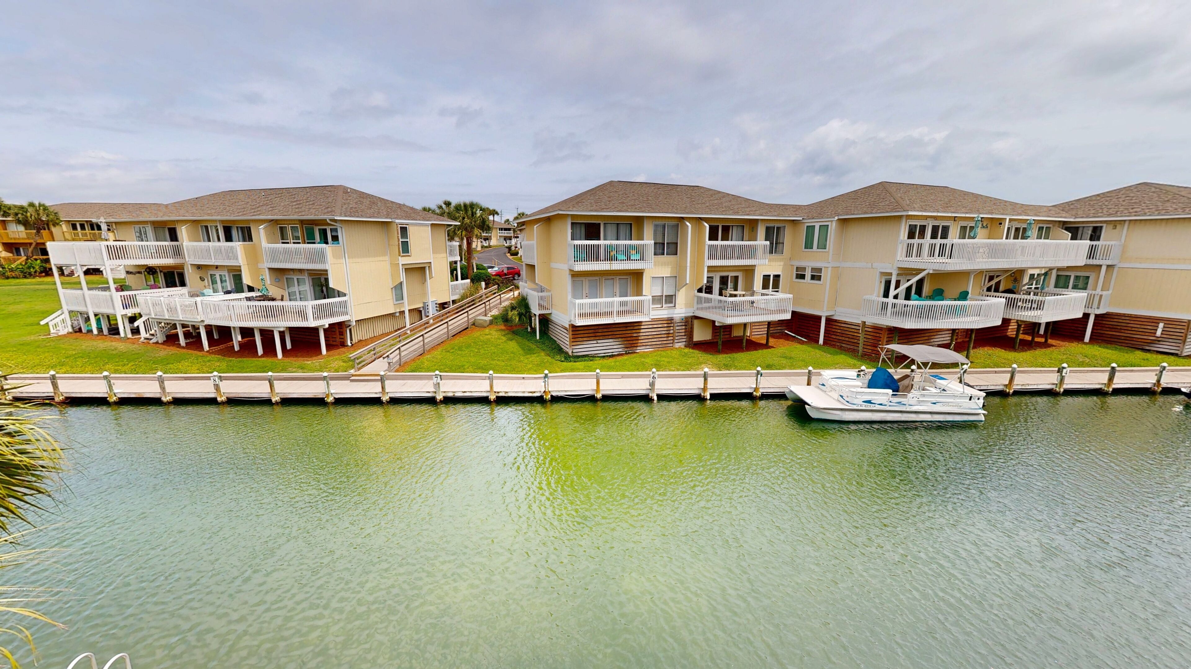 A waterfront hotel with multiple balconies, a dock, and a boat.