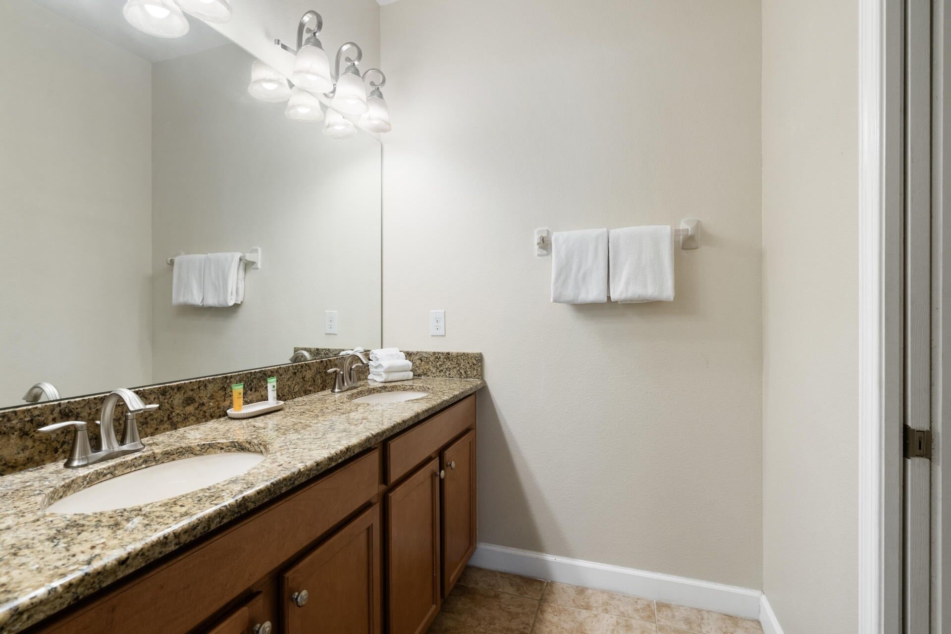 Un baño con dos lavamanos, un espejo y un perchero para toallas.
