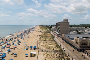 Eine Strandpromenade mit Strandstühlen, einem Promenadenweg und einem Gebäude mit der Aufschrift 'Funland'.