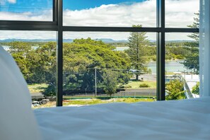 A room with a large window offering a view of a park, trees, and a distant body of water. - Solaris 509: 2  BR, 1  BA Apartment in Forster, Sleeps 4 (Forster)