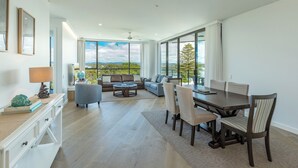 Ein großzügiger Wohnbereich mit Esstisch, Sofa und Sesseln, große Fenster mit Blick ins Freie.