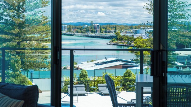 Ein Balkon mit Blick auf einen Fluss, Gebäude und Grünflächen.