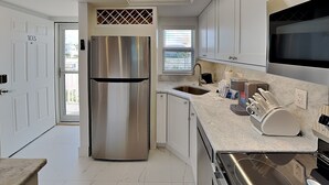 Uma cozinha moderna com geladeira de aço inoxidável, forno embutido e micro-ondas.