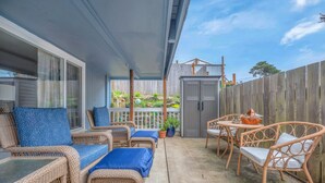 A covered patio with wicker furniture, a small table, and a potted plant. - Beach Nest: Modern Coastal Getaway Near Ocean, Trails & Dining (Lincoln City)