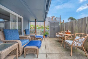Une terrasse couverte, aménagée avec des meubles en osier, une petite table et une plante en pot.