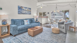 A modern living room with a blue sofa, ottoman, and a rug. - Beach Nest: Modern Coastal Getaway Near Ocean, Trails & Dining (Lincoln City)