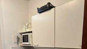 Une petite cuisine équipée d’un four à micro-ondes, d’une machine à café et d’un évier.