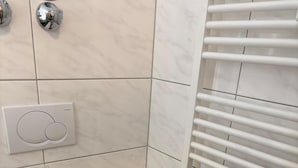 Une salle de bain équipée d’un WC, d’un porte-serviettes, d’un support à papier toilette et d’un radiateur.