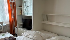 Une chambre d’hôtel avec deux lits, une télévision, une bibliothèque et une fenêtre avec des rideaux.